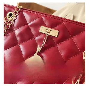 Detail of wine red quilted leather bag featuring gold deer charm and rectangular lock