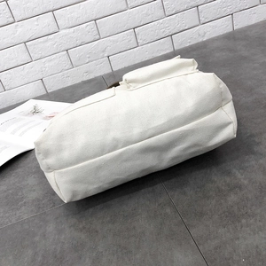 Detail view of the durable cream canvas fabric and rectangular side pocket on the bag