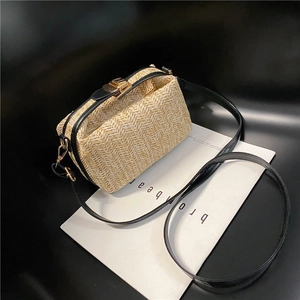 Detail of woven straw handbag featuring black leather trim and gold metal clasp closure