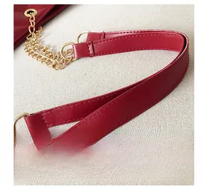 Detail of red leather shoulder strap with gold chain links and precision stitching