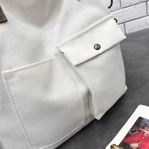 Detail of off-white canvas tote with dual pockets and dark brown fabric handles