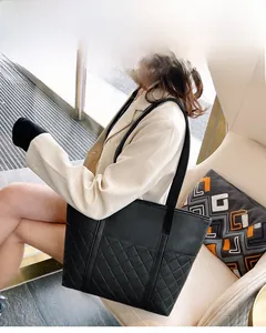 Close-up of a black tote bag with quilted diamond pattern and long shoulder straps
