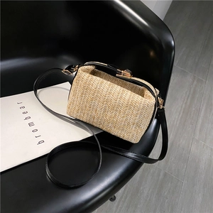Detailed close-up of woven crossbody bag with black leather trim and golden clasp