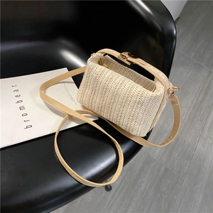 Detailed view of woven straw bag with beige herringbone texture and golden buckle