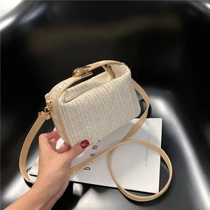 Close-up of beige woven crossbody bag with metal buckle and slim leather strap detail
