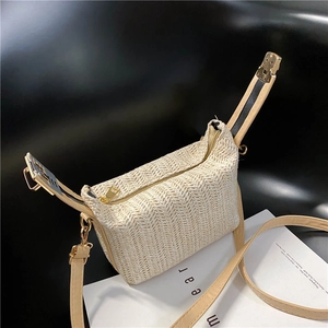 Detail of woven straw bag showing the zipper closure and adjustable brown leather strap