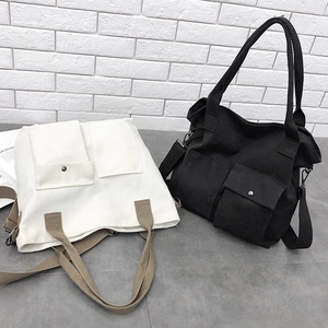 Detail view of canvas tote bags featuring double front flap pockets and adjustable straps