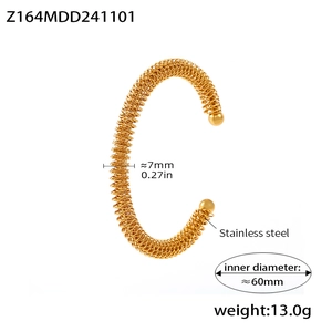 Macro detail of gold-plated stainless steel spring cuff bracelet showing 7mm width and texture