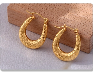 Macro shot of 18K gold-plated stainless steel earrings with embossed scale texture