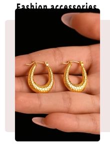 Close-up of gold U-shaped hoop earrings with snakeskin texture held by hand