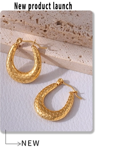 Macro shot of gold-plated fish scale textured hoop earrings on minimalist stone stand