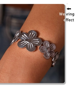 Detail of silver five-petal flower bracelet with textured petals on a model's wrist