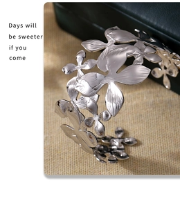 Detailed view of silver flower textured cuff bracelet with wide open floral patterns