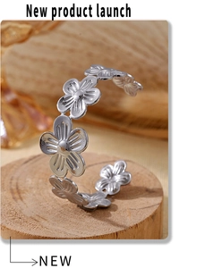 Macro shot of silver floral open cuff bracelet with daisy petals on wooden tray