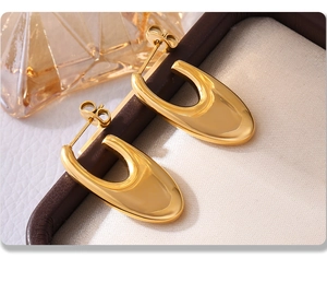 Detailed macro view of gold-plated teardrop earrings on a beige silk jewelry display tray