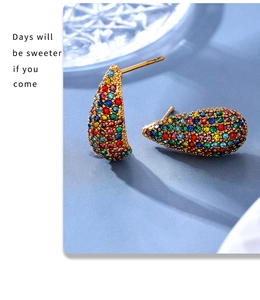 Macro detail of teardrop stud earrings with colorful pavé crystals and 18K gold PVD plating