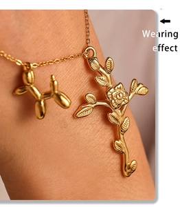 Detailed view of gold bracelet featuring balloon dog and rose cross charms on a model wrist