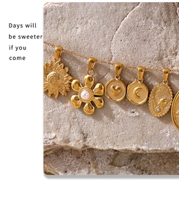 Detail of 18K gold plated necklace with vintage heart and flower charms on stone surface