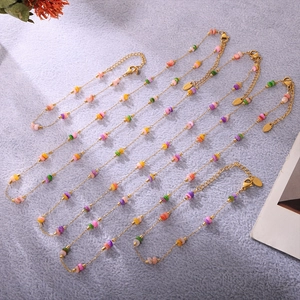 Détail de perles colorées sur chaînes en acier doré sur un fond texturé gris élégant