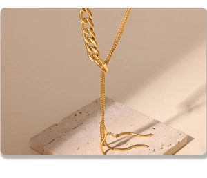 Makro-Detail einer 18k vergoldeten Edelstahl-Schichtenkette mit Quasten auf Stein
