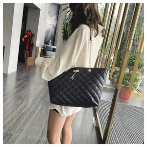 Detailed side view of black quilted tote bag with gold chain and deer charm pendant