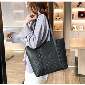 Detail of large black leather tote bag with elegant quilted stitching on the lower part