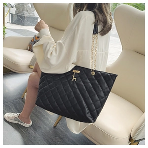Close-up of black quilted tote bag featuring gold chain strap and a deer charm detail
