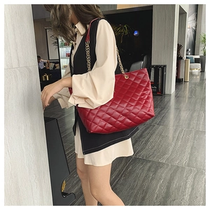 Detailed view of a red quilted chain shoulder bag shown on model in a modern interior