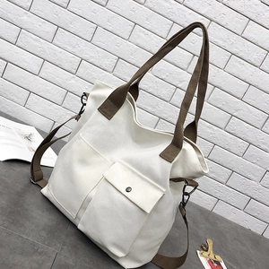 Detail of off-white canvas tote with brown straps and dual front utility pockets