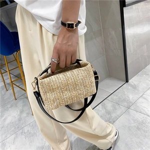 Handwoven straw handbag with black leather handles and adjustable shoulder strap