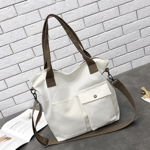Detail of white canvas tote bag with brown straps and dual front pockets