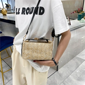 Detail of woven straw crossbody bag featuring wave texture and black leather handle