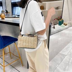 Detail of woven straw crossbody bag with gold-tone hardware and adjustable leather strap