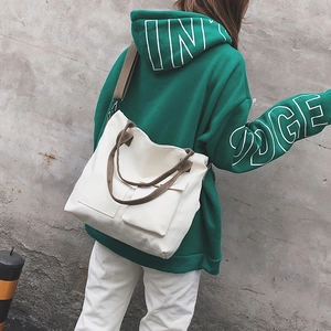 Detailed shot of white canvas tote bag with khaki straps worn as a crossbody bag