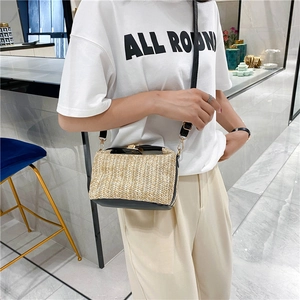 Detail of woven straw crossbody bag with black leather trim and gold metal clasp