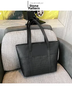 Detail of black tote bag showing smooth leather texture and stone pattern embossing