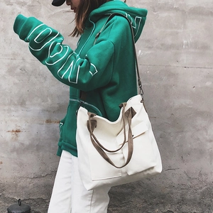 Detail of minimalist canvas crossbody bag with two front pockets and durable brown straps