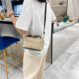 Modern woven straw crossbody bag worn by a model in a stylish interior setting