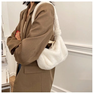 Detail of white plush shoulder bag featuring soft faux fur texture and a wide strap