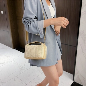 Detailed texture of the woven straw material and leather strap on this crossbody bag