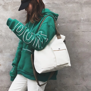 Detailed shot of an off-white canvas crossbody bag with dark brown straps on a model