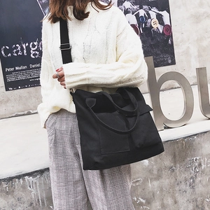Detail of black multi-pocket canvas bag worn crossbody with adjustable shoulder strap