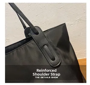 Macro detail of reinforced shoulder strap stitching on a black nylon tote bag