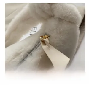 Détail du zip en métal doré et de la tirette en cuir crème sur un sac en peluche blanc doux
