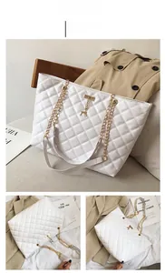Detail of white quilted tote bag with gold deer charm and chain shoulder strap