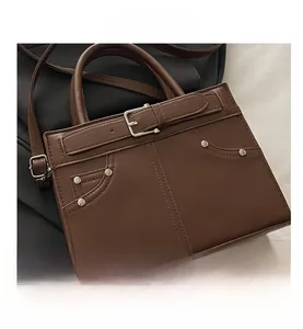 Détail d'un sac à main marron vintage avec des rivets métalliques et des coutures de poche