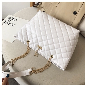 Detail of white quilted tote bag with golden chain strap and deer charm on a soft background
