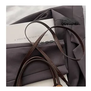 Detail eines dunkelbraunen Leder-Schultergurts mit feinen Nähten an einer Tasche