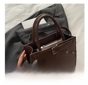 Détail d'un sac cabas marron en cuir avec fermetures éclair et boucles métalliques chics
