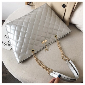 Close-up of silver quilted tote bag featuring metallic finish and gold deer charm